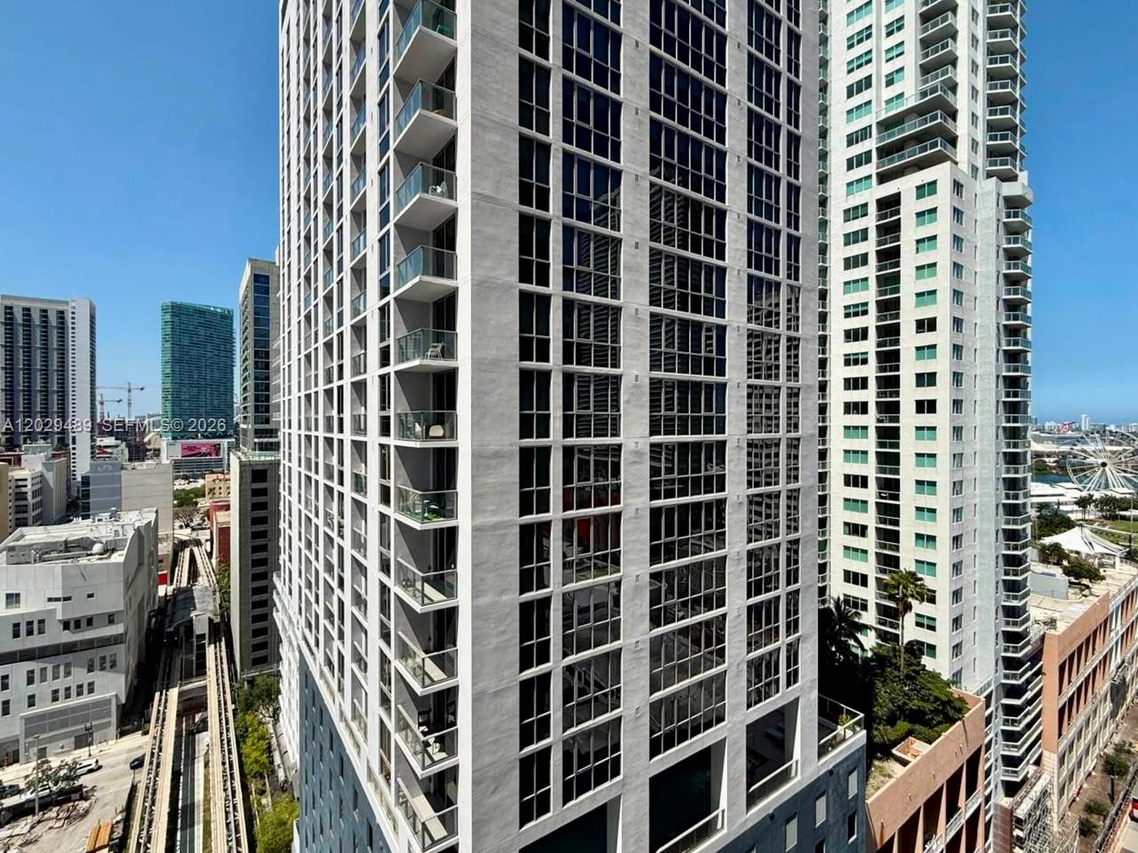 An exterior view of a modern high-rise apartment building with balconies and glass windows — 133 NE 2nd Ave # 1905, Miami FL 33132, MIAMI, FL