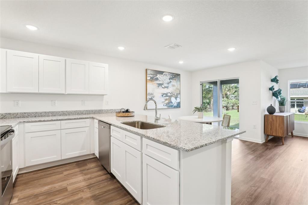 A dining area features a round table, two chairs, a wooden sideboard, and sliding glass doors — 7508 PENNY LANE, FORT PIERCE, FL