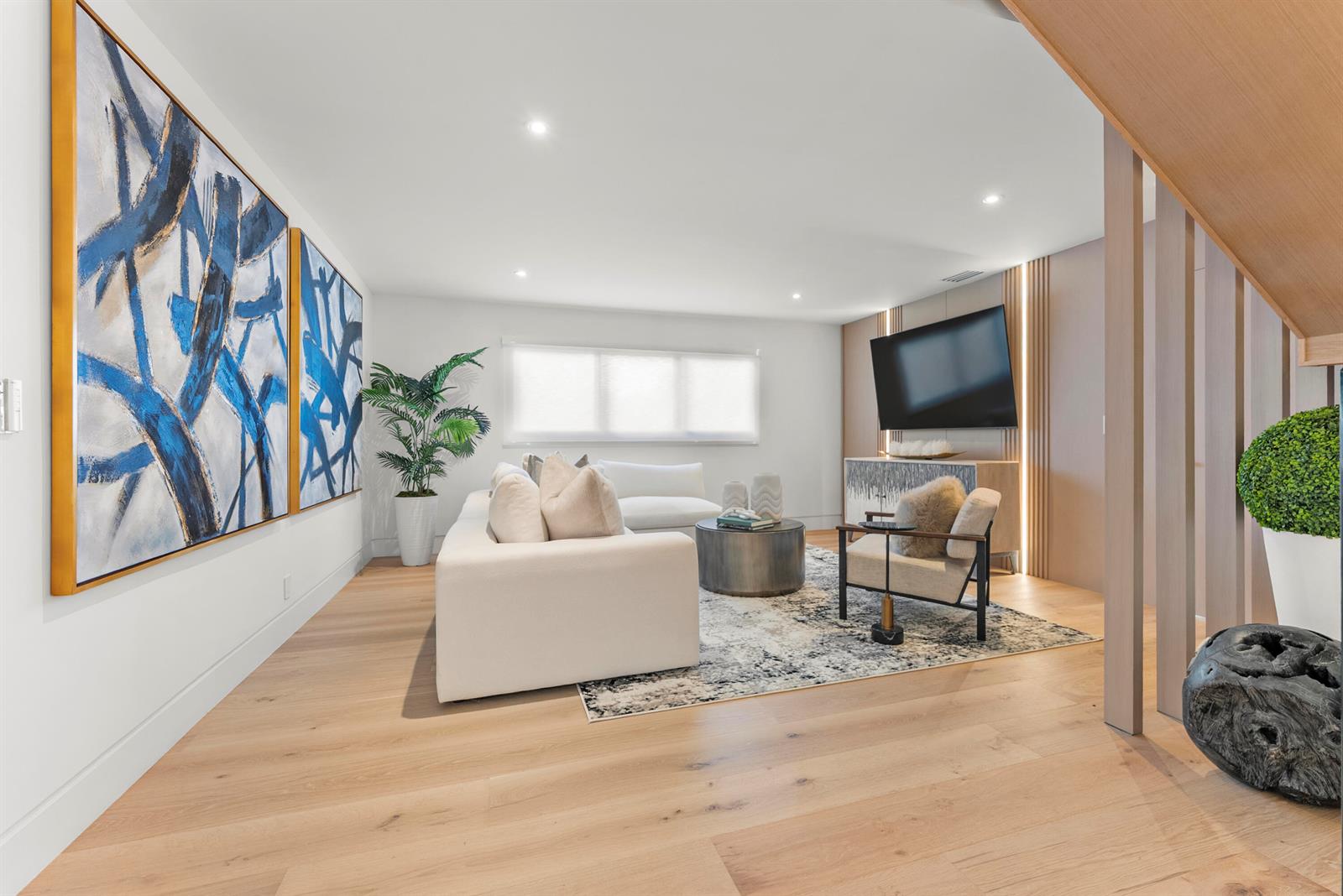 A modern living room features light wood floors, a white sectional, and blue abstract art — 1690-1692 S Ocean Boulevard, Delray Beach FL 33483, DELRAY BEACH, FL