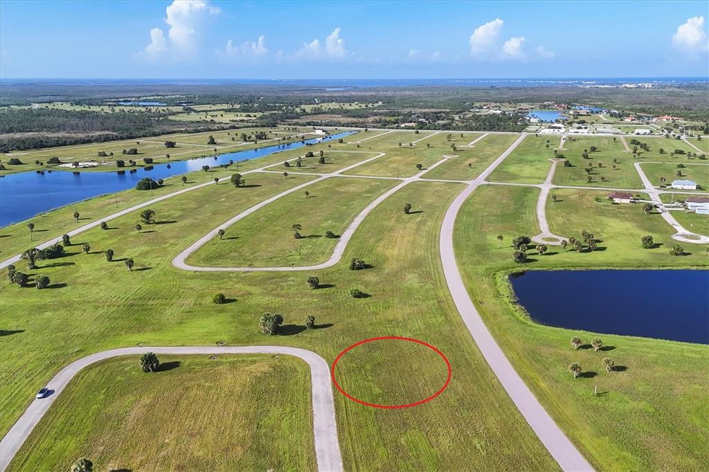 An aerial view shows a vacant grassy lot outlined in red within a residential development — 23 REDWOOD DRIVE, PLACIDA, FL