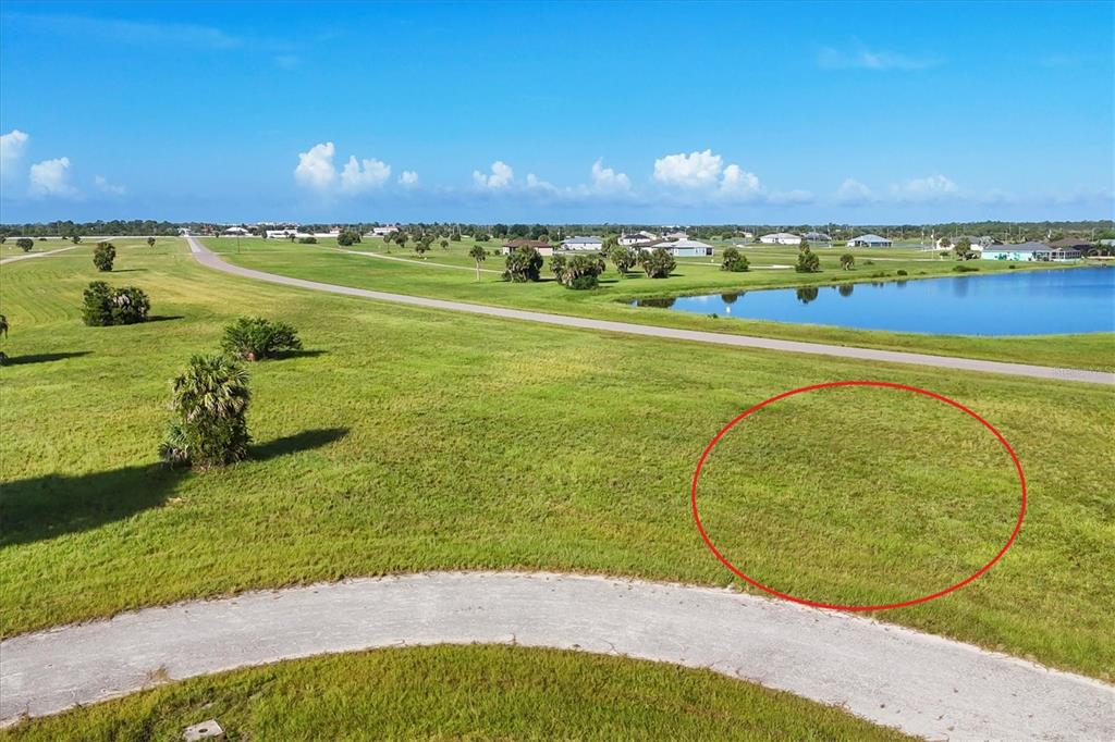 An aerial view shows a vacant grassy lot circled in red near a paved road — 23 REDWOOD DRIVE, PLACIDA, FL