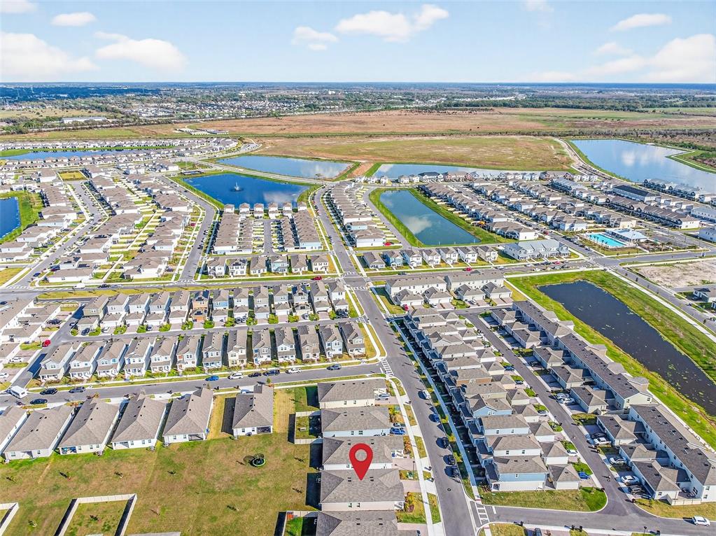 This aerial view shows a residential neighborhood with houses, ponds, and a marked property — 2619 PEACE OF MIND AVENUE, KISSIMMEE, FL