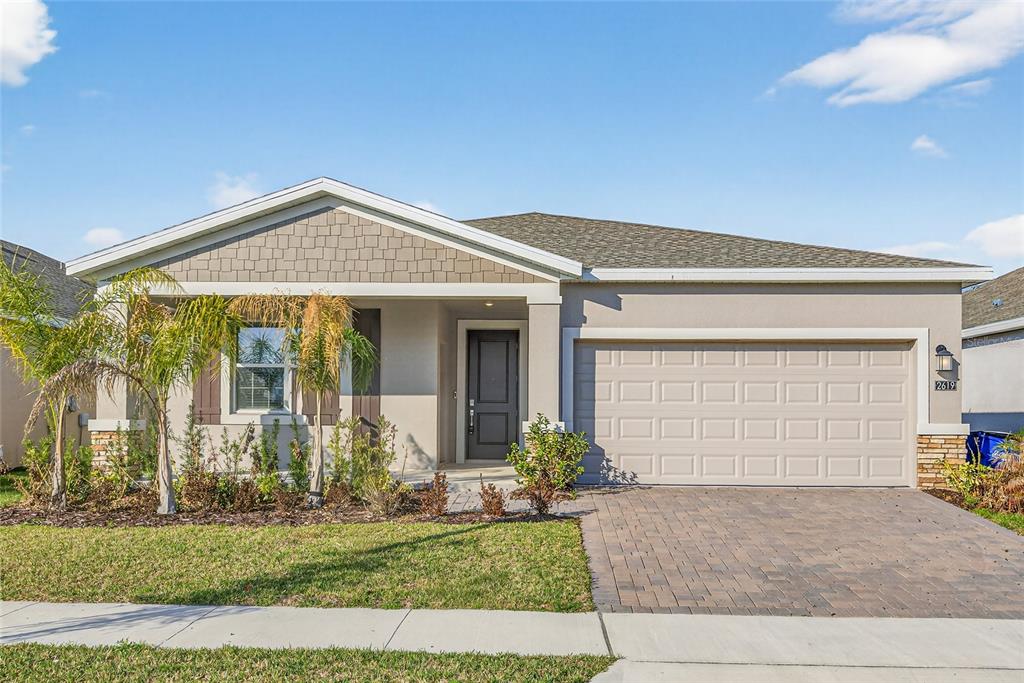 A single-story suburban house with a paved driveway, two-car garage, and a front porch — 2619 PEACE OF MIND AVENUE, KISSIMMEE, FL