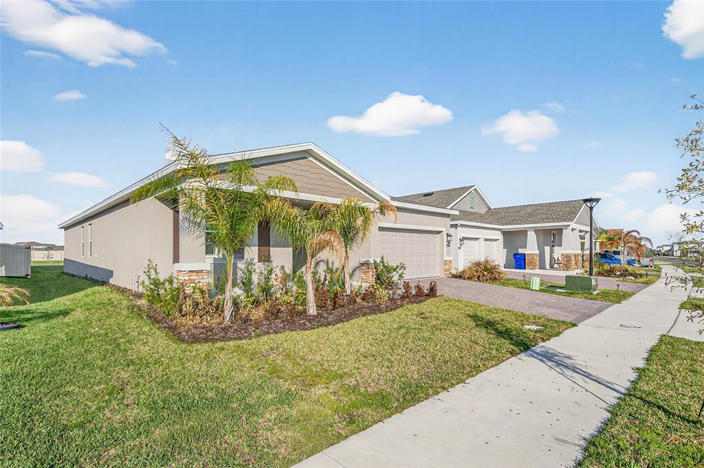 A single-story suburban house with a paved driveway, palm trees, and a grassy front yard — 2619 PEACE OF MIND AVENUE, KISSIMMEE, FL