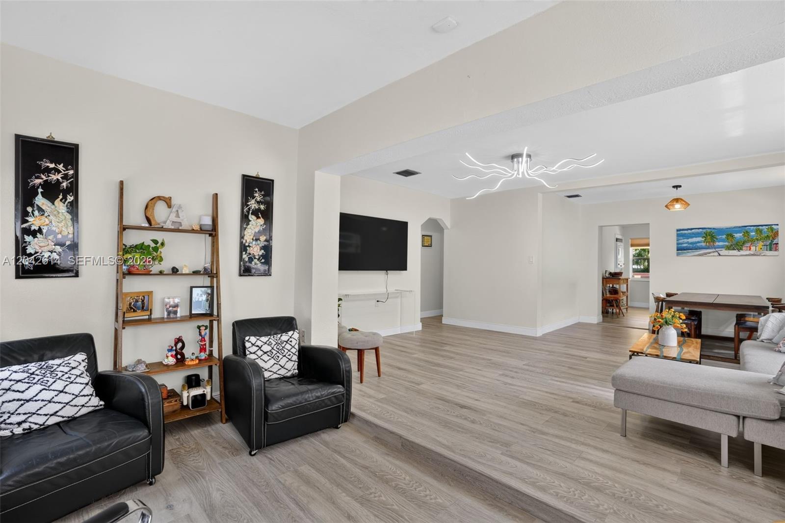 A living room with light wood floors, a sunken seating area, and a modern chandelier — 2446 Mckinley St, Hollywood FL 33020, HOLLYWOOD, FL