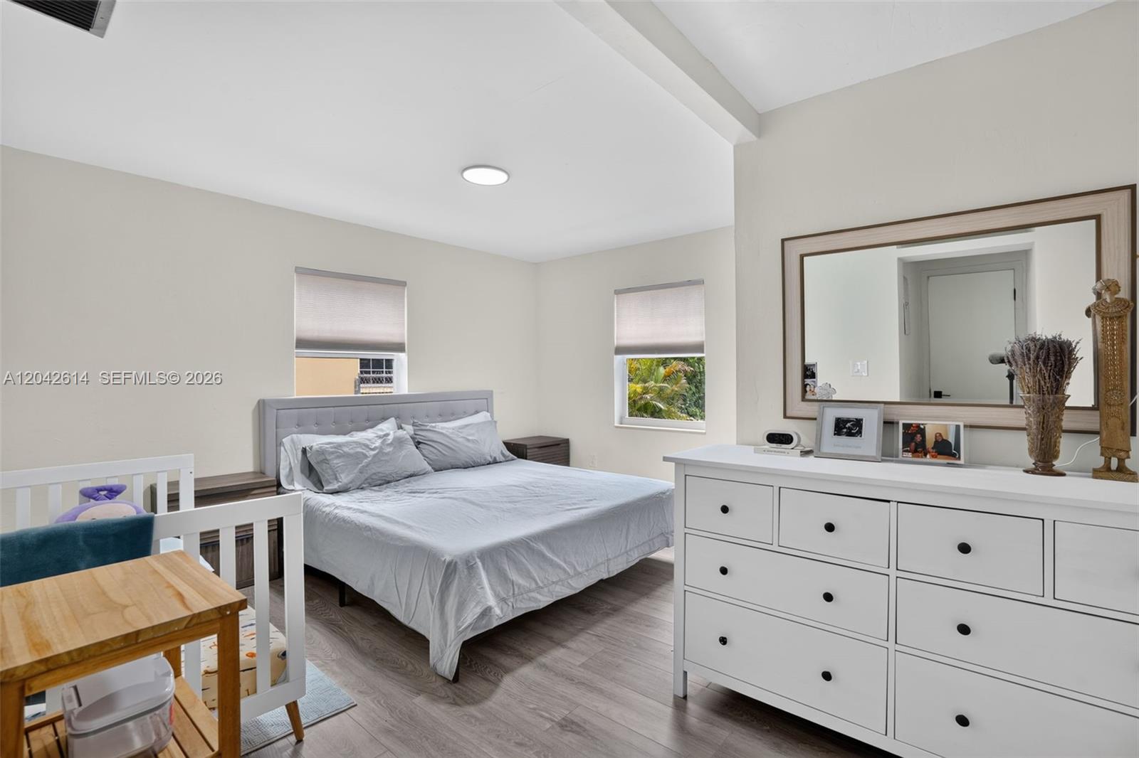 A bedroom features a bed, a white dresser, a crib, and light wood flooring — 2446 Mckinley St, Hollywood FL 33020, HOLLYWOOD, FL