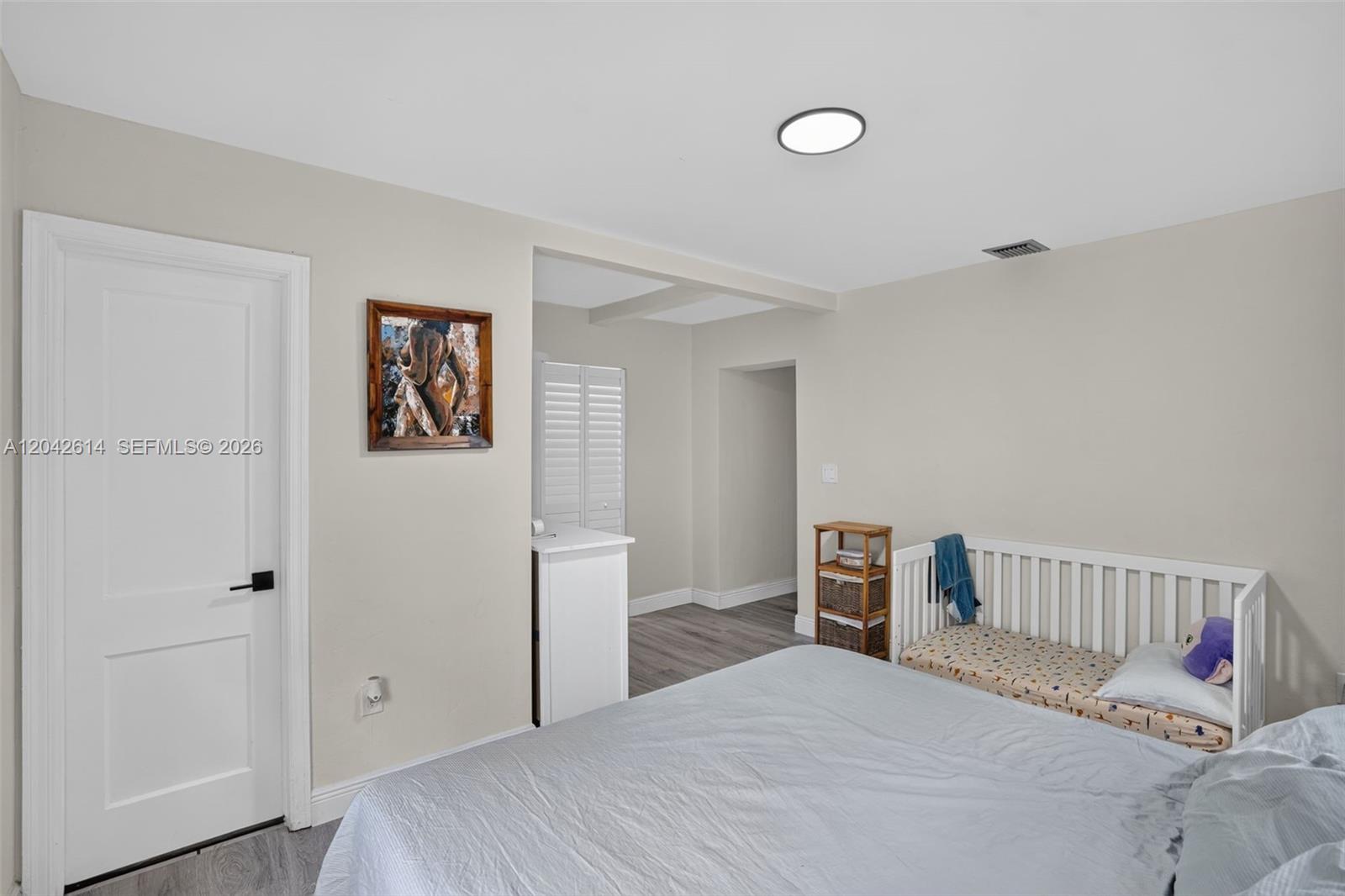 A bedroom features light gray walls, wood-look flooring, a white crib, and a doorway — 2446 Mckinley St, Hollywood FL 33020, HOLLYWOOD, FL