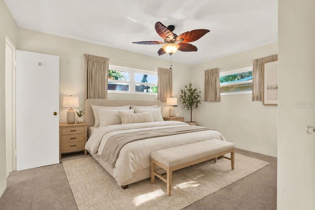 A bedroom features a bed with neutral bedding, a ceiling fan, and two windows — 2561 58TH STREET N, ST PETERSBURG, FL