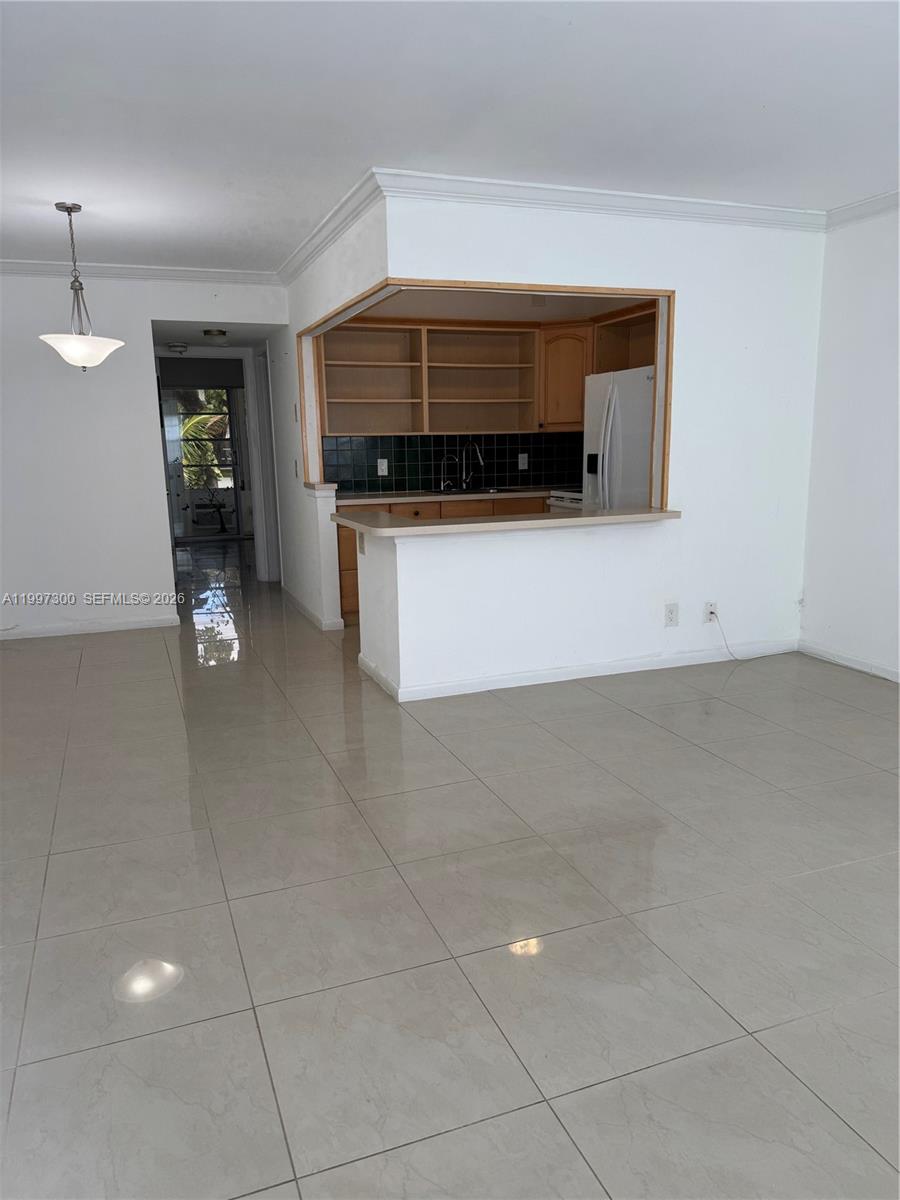 A kitchen with wood cabinets and a breakfast bar opens into a tiled living area — 162 Westbury J # 162, Deerfield Beach FL 33442, DEERFIELD BEACH, FL