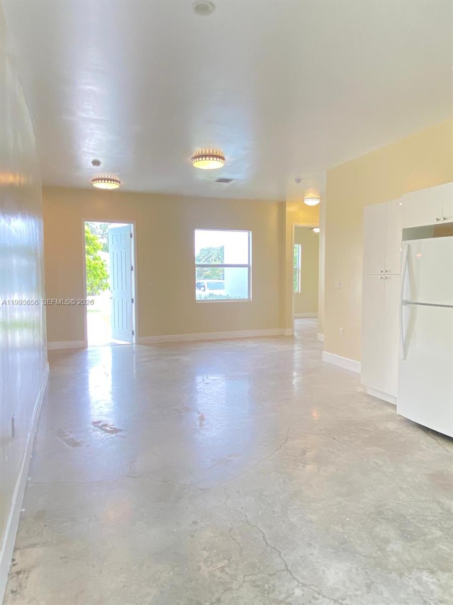 An open-concept room features a polished concrete floor, white cabinetry, and a refrigerator — 12150 SW 213th St # 12150, Miami FL 33177, MIAMI, FL