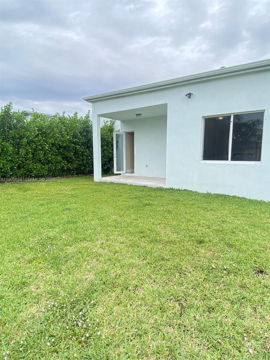 A view of a backyard with a grass lawn and a covered patio area — 12150 SW 213th St # 12150, Miami FL 33177, MIAMI, FL