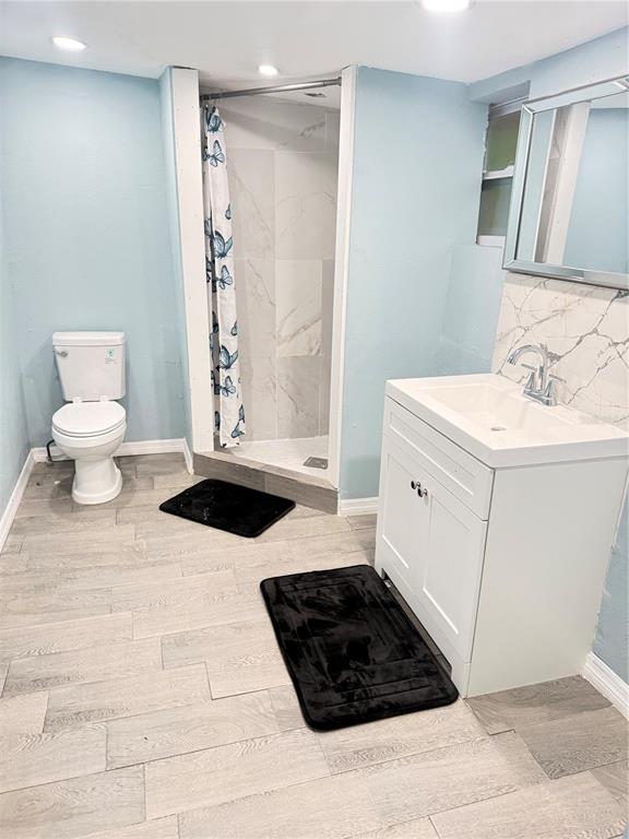 A bathroom features light blue walls, a white vanity, a toilet, and a tiled shower — 2135 ORANGE DRIVE, HOLIDAY, FL
