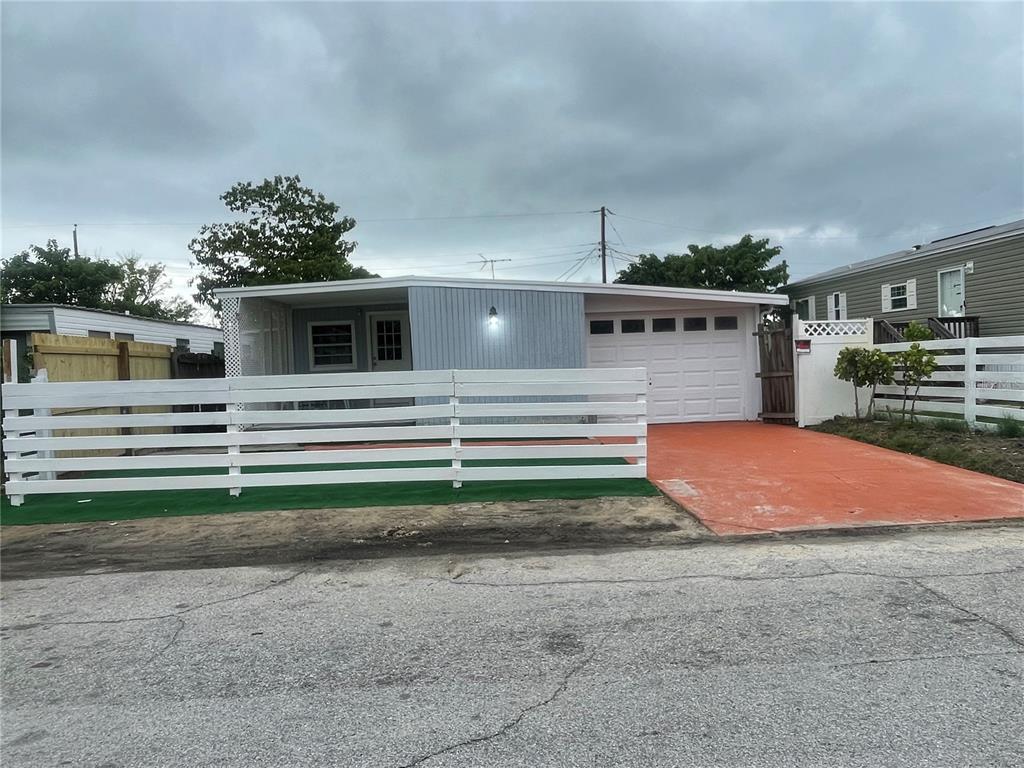 A single-story house with a white horizontal fence, a red driveway, and a garage — 2135 ORANGE DRIVE, HOLIDAY, FL