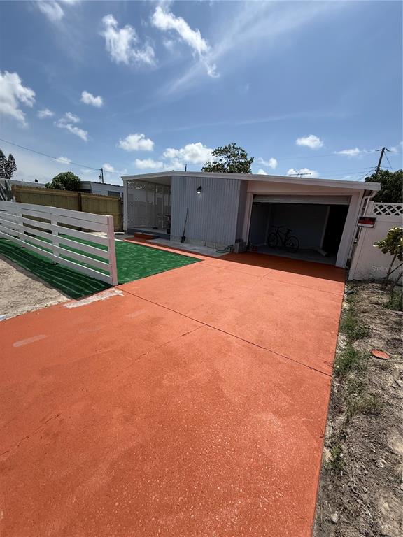 A house exterior features a red painted driveway, a white fence, and a covered carport — 2135 ORANGE DRIVE, HOLIDAY, FL