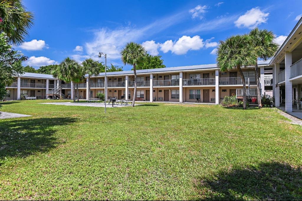 A two-story apartment building with exterior walkways and palm trees overlooks a grassy courtyard — 4410 N HALE AVENUE, TAMPA, FL