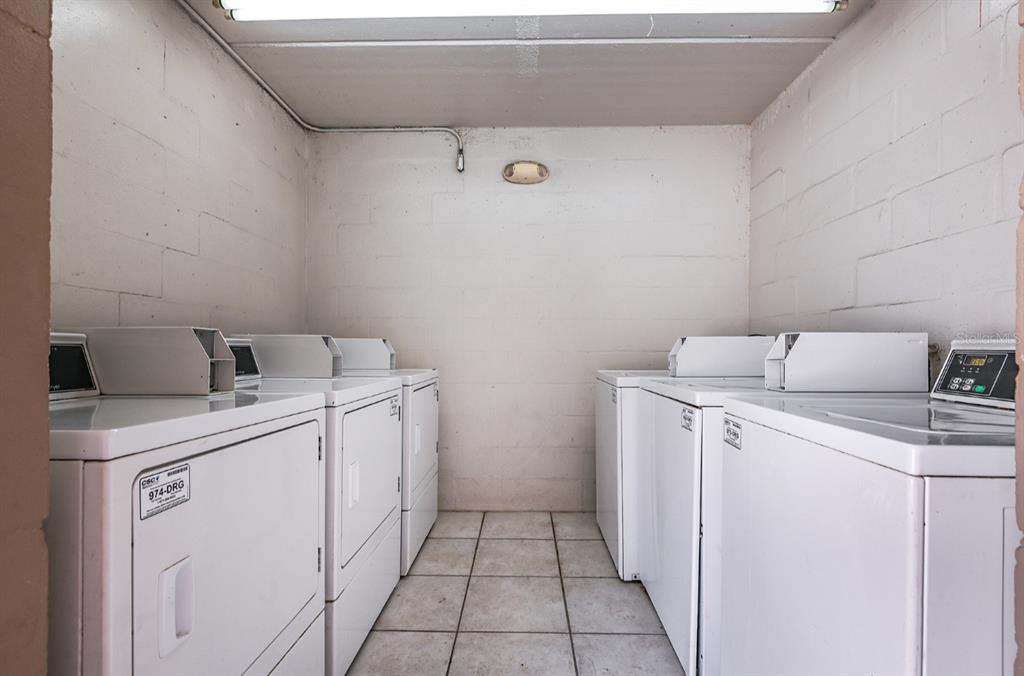 A laundry room with white block walls, tile flooring, and several white coin-operated dryers — 4410 N HALE AVENUE, TAMPA, FL