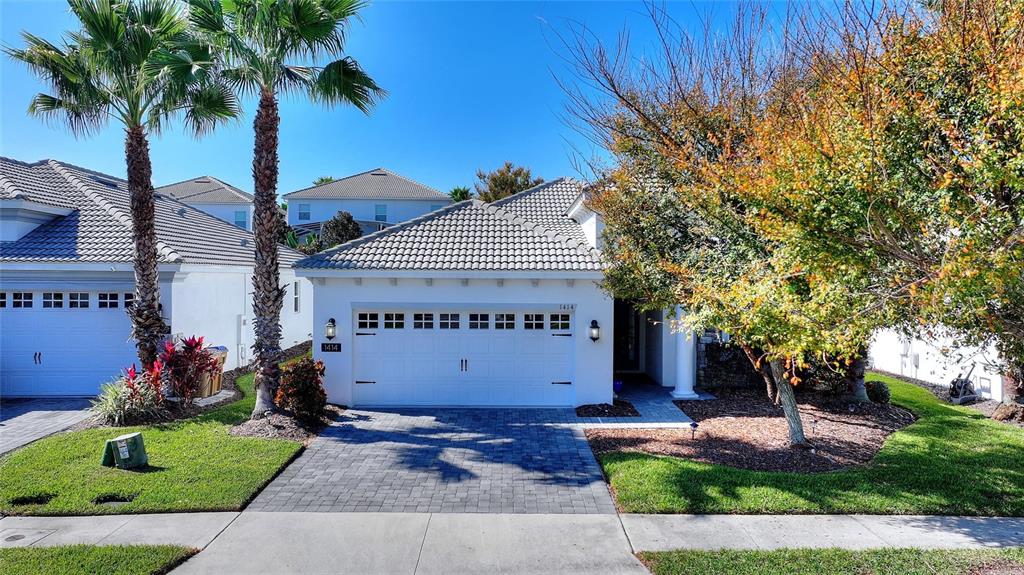 A single-story suburban house features a white garage, a paved driveway, and two palm trees — 1414 CLUBMAN DR, DAVENPORT, FL