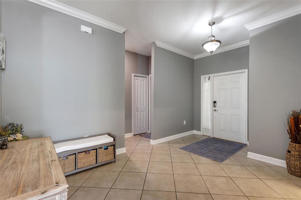 An entryway features gray walls, tile flooring, a white front door, and a storage bench — 1414 CLUBMAN DR, DAVENPORT, FL