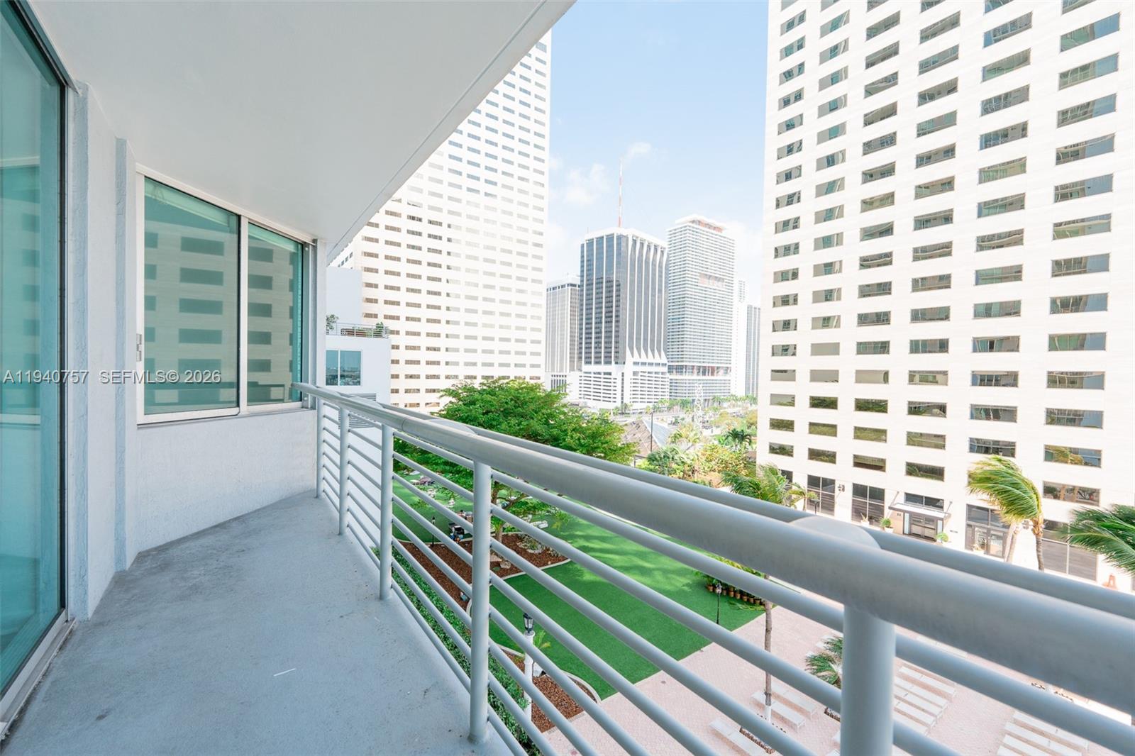 A balcony with a metal railing overlooks a courtyard and surrounding city skyscrapers — 335 S Biscayne Blvd # 1108, Miami FL 33131, MIAMI, FL