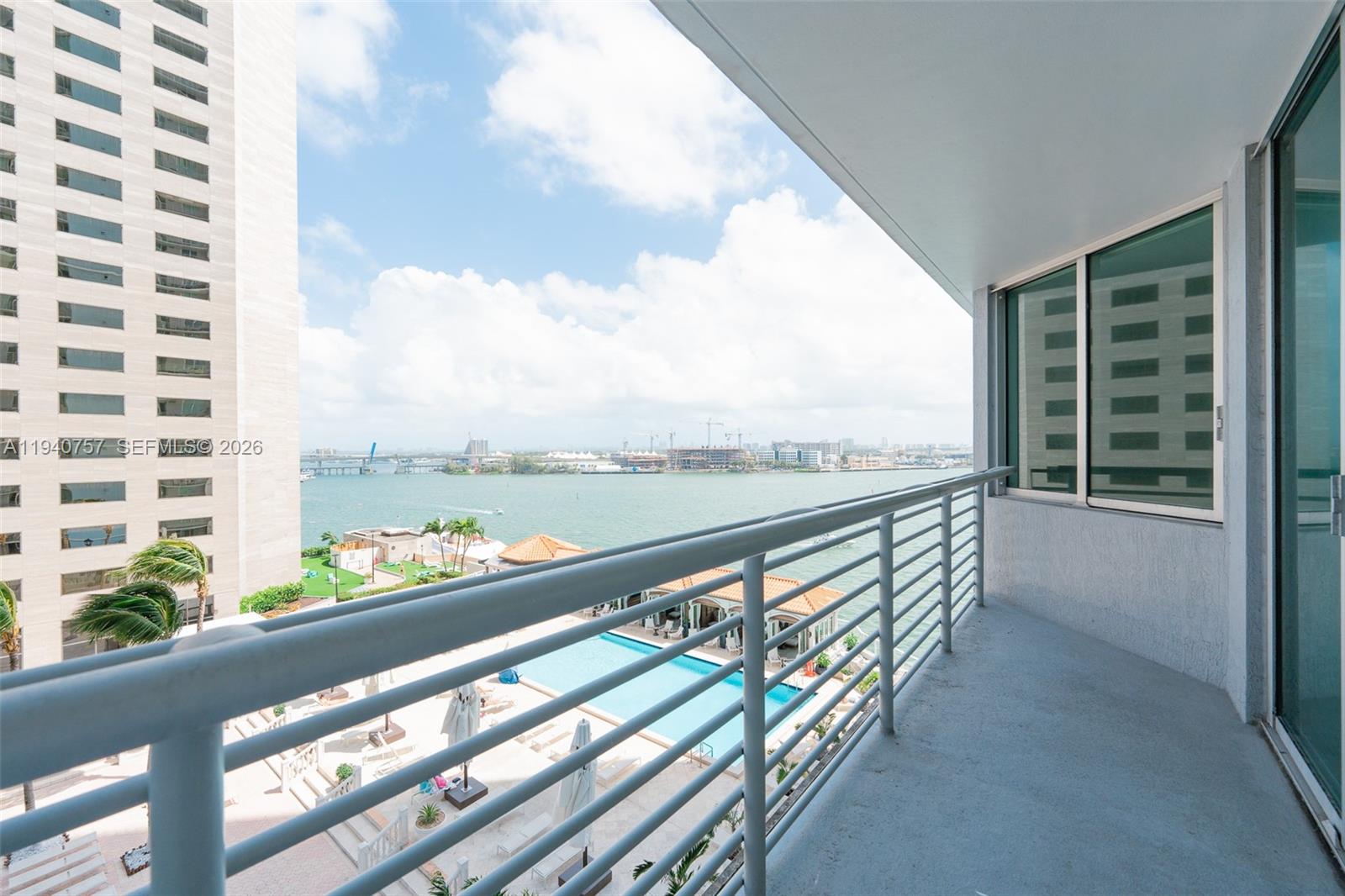 A balcony with a metal railing overlooks a swimming pool and a bay — 335 S Biscayne Blvd # 1108, Miami FL 33131, MIAMI, FL