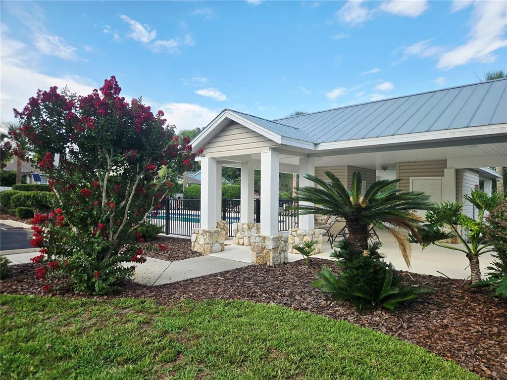 A covered outdoor patio with stone-based columns sits beside a blooming crape myrtle tree — 1611 NW 121ST WAY, GAINESVILLE, FL