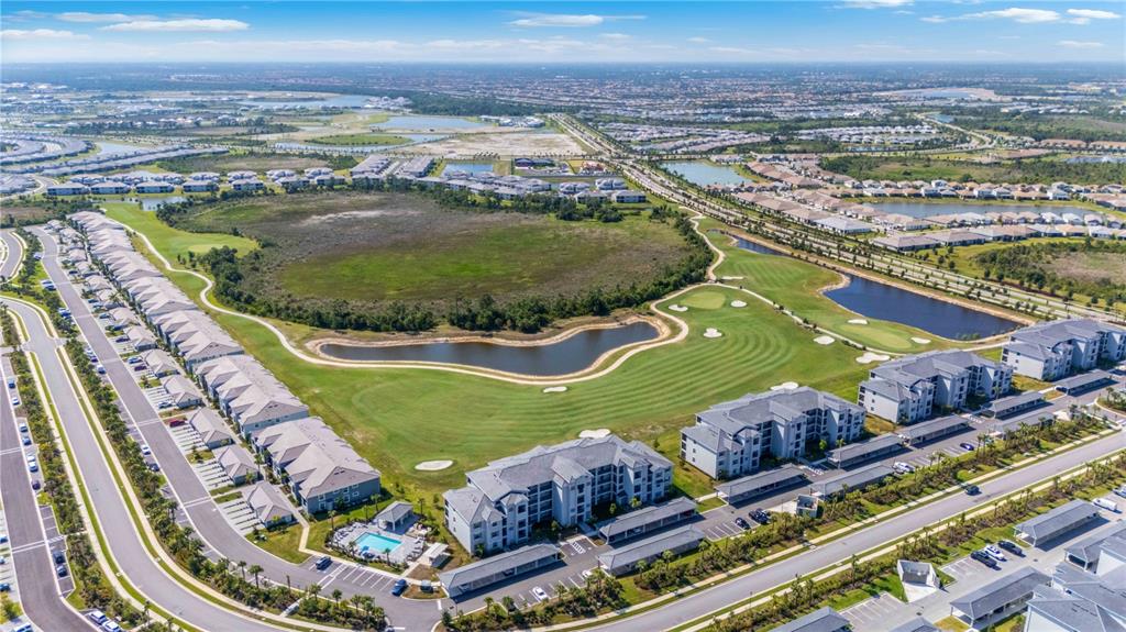 An aerial view shows a residential complex with apartment buildings, a golf course, and ponds — 17565 OPAL SAND DRIVE UNIT 401, VENICE, FL