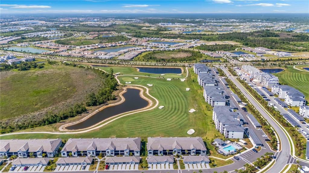 An aerial view shows apartment buildings, a golf course, and several ponds in a suburban area — 17565 OPAL SAND DRIVE UNIT 401, VENICE, FL