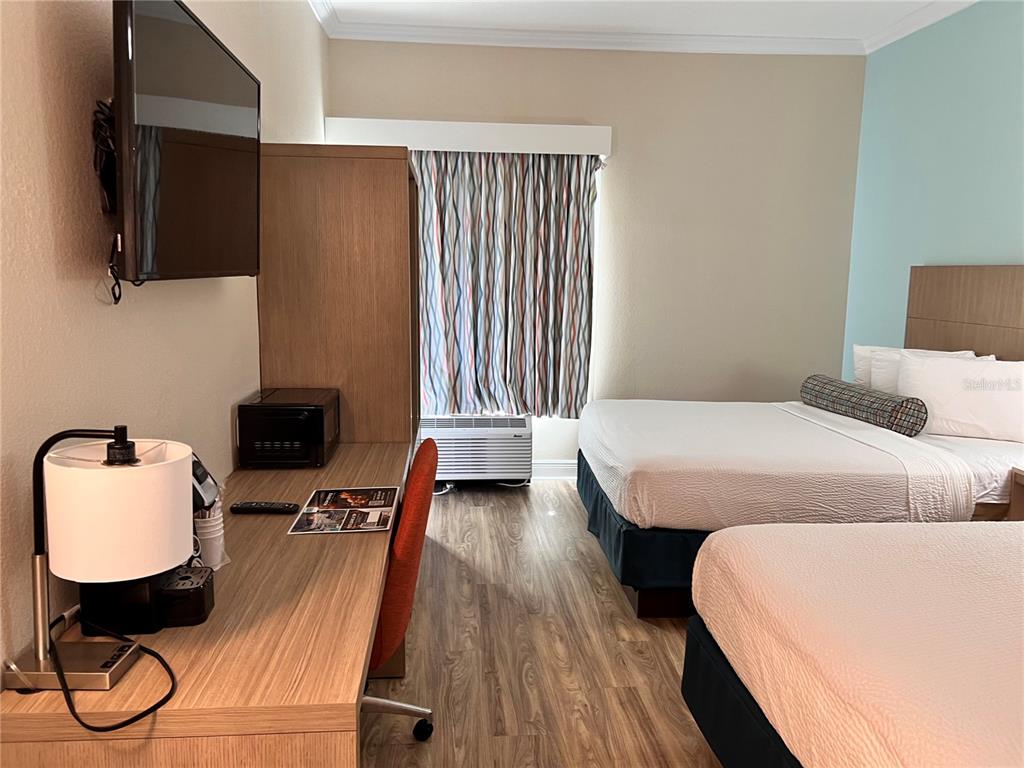 A hotel room features two beds, a desk with a chair, and a wall-mounted television — 3000 MAINGATE LANE UNIT 122, KISSIMMEE, FL
