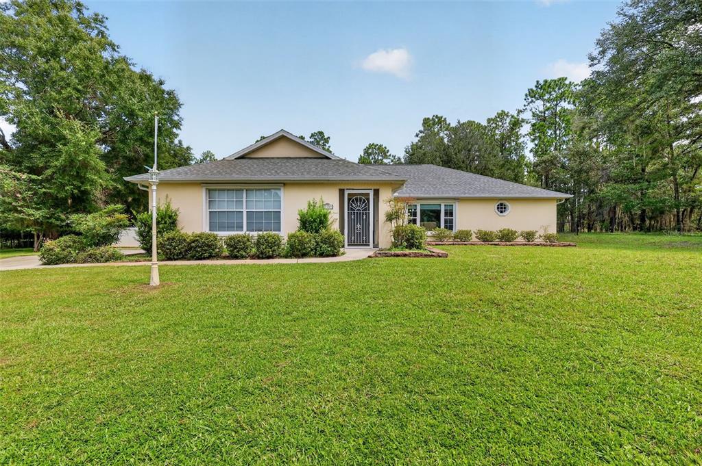 A single-story house with a light-colored exterior, a gray roof, and a large front lawn — 21859 SW 82ND STREET, DUNNELLON, FL