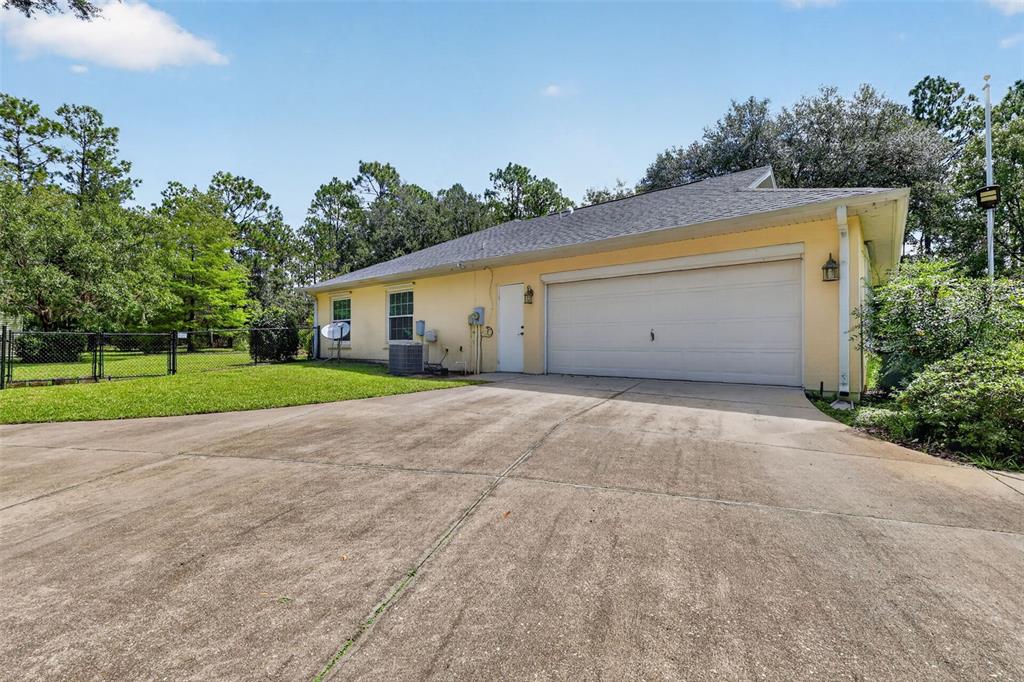 A yellow house with a two-car garage and a concrete driveway sits on a grassy lot — 21859 SW 82ND STREET, DUNNELLON, FL
