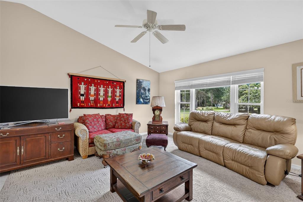 A living room features a tan leather sofa, a patterned loveseat, and a wooden coffee table — 21859 SW 82ND STREET, DUNNELLON, FL