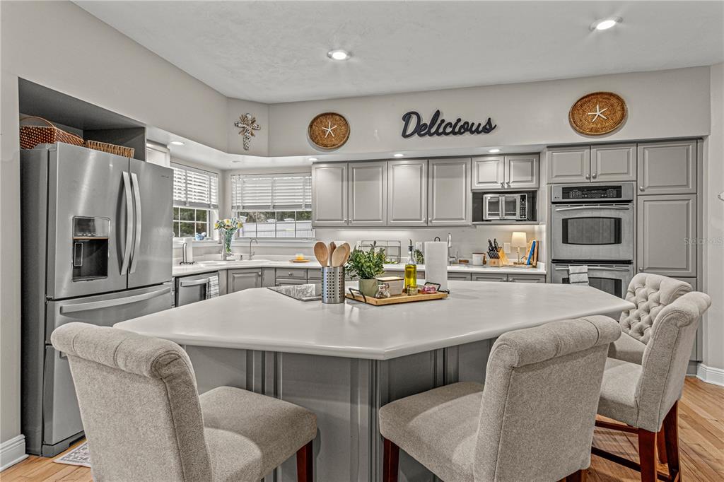 A kitchen features gray cabinets, stainless steel appliances, and a large central island with seating — 649 CHARMAGNE LANE, PORT ORANGE, FL