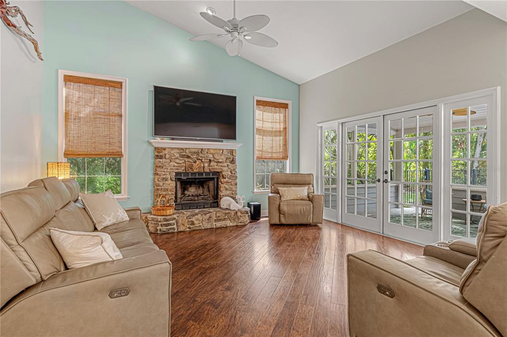 A living room features a stone fireplace, light blue accent wall, and glass patio doors — 649 CHARMAGNE LANE, PORT ORANGE, FL