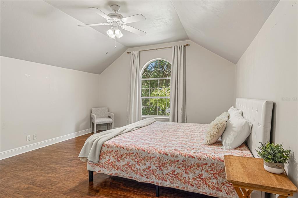 A bedroom with dark wood flooring, a vaulted ceiling, and an arched window with curtains — 649 CHARMAGNE LANE, PORT ORANGE, FL