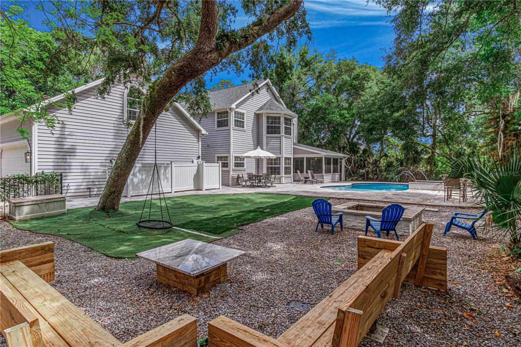 A backyard features a swimming pool, a gravel fire pit area, and a grassy lawn — 649 CHARMAGNE LANE, PORT ORANGE, FL