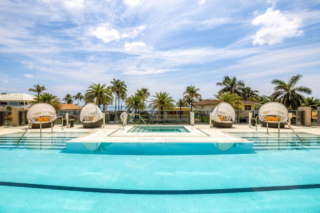 A swimming pool with a central hot tub and four lounge chairs on a sunny deck — 305 Briny Avenue # 706, Pompano Beach FL 33062, POMPANO BEACH, FL