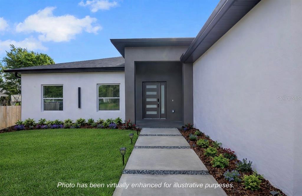 A modern house exterior features a gray entryway, white walls, and a concrete walkway — 1231 DUNBAR AVENUE, SANFORD, FL