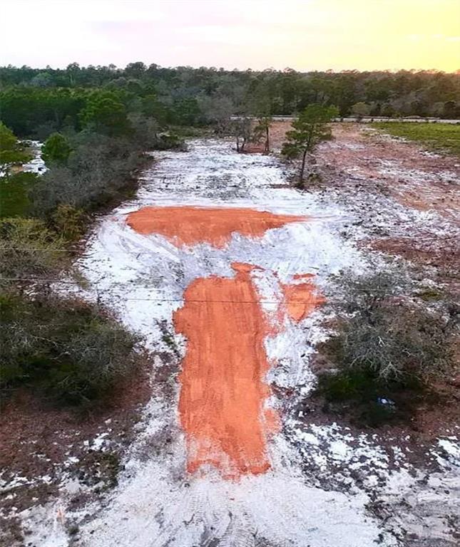 An aerial view shows a cleared, sandy lot with patches of exposed red clay soil — WOODSTORK WAY, FROSTPROOF, FL