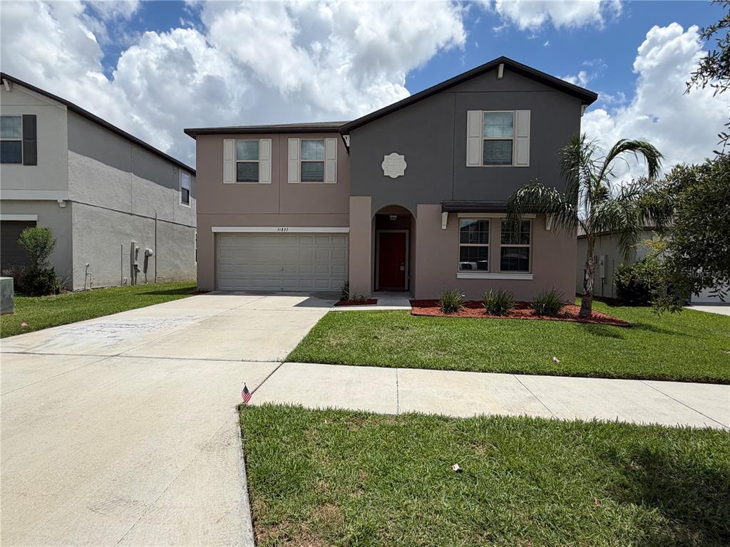 A two-story house with a two-car garage, gray and tan exterior, and a front lawn — 31823 SUN KETTLE LOOP, WESLEY CHAPEL, FL