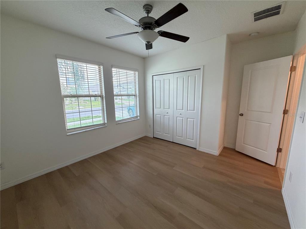 A bedroom with light wood flooring, white walls, a ceiling fan, and two windows — 31823 SUN KETTLE LOOP, WESLEY CHAPEL, FL
