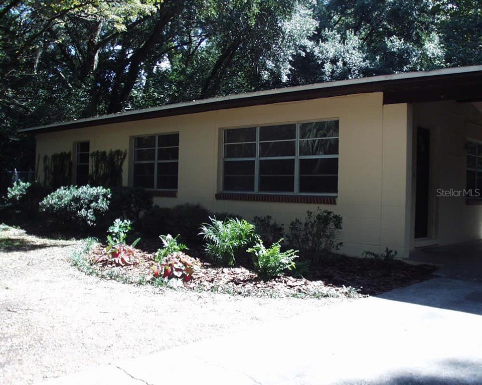 A single-story house with a beige exterior, large windows, and a front carport — 621 NW 36TH DRIVE, GAINESVILLE, FL