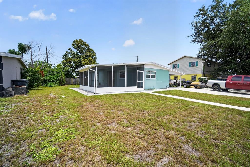 The exterior of a single-story house features a screened-in porch and a large grassy yard — 6115 FREEMONT STREET, NORTH PORT, FL