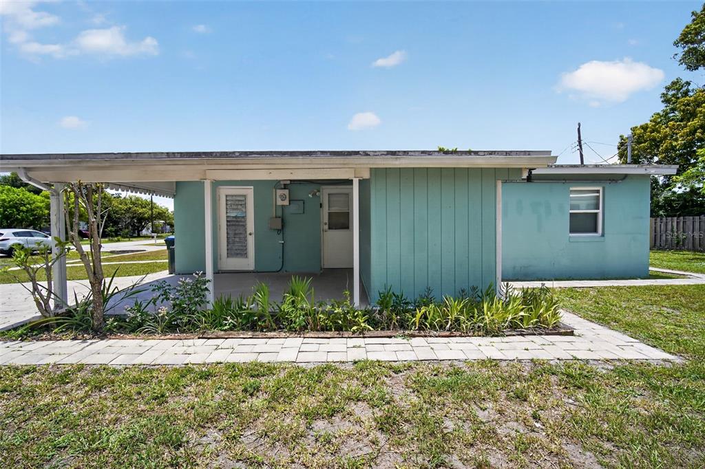 A teal single-story house features a covered patio, a paved walkway, and a grassy yard — 6115 FREEMONT STREET, NORTH PORT, FL