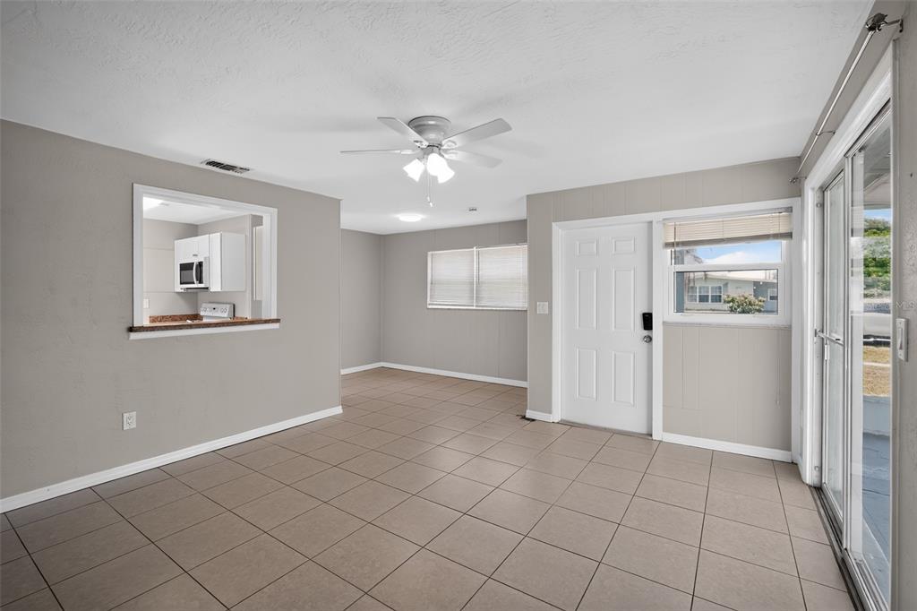 A tiled dining area features a ceiling fan, a kitchen pass-through, and a sliding door — 6115 FREEMONT STREET, NORTH PORT, FL