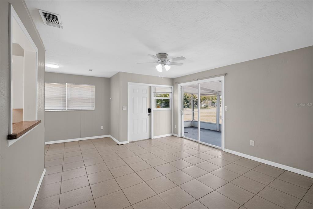 A room with light gray walls, tiled floors, a ceiling fan, and a sliding glass door — 6115 FREEMONT STREET, NORTH PORT, FL