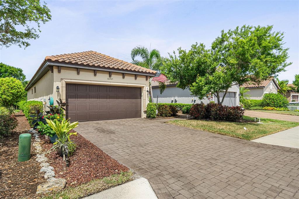 A single-story house with a brown garage door, tile roof, and a paved driveway — 10205 SAINT FRANCIS TERRACE, PALMETTO, FL