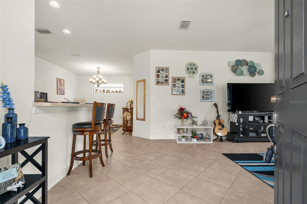 An open-concept living area features tile flooring, a breakfast bar, and a television console — 10205 SAINT FRANCIS TERRACE, PALMETTO, FL