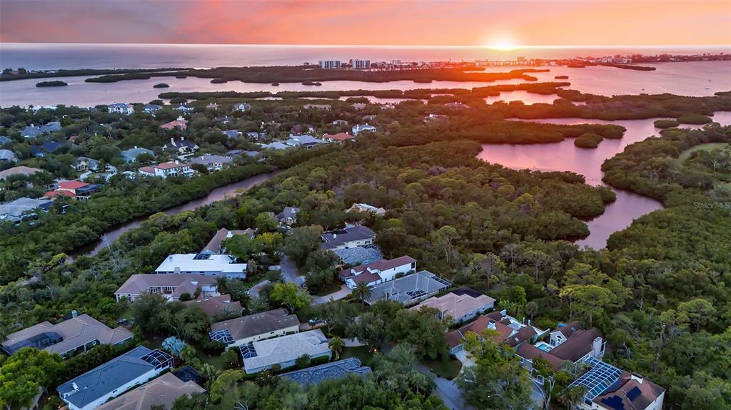 An aerial view of a coastal residential neighborhood surrounded by mangroves at sunset — 156 BISHOPS COURT ROAD, OSPREY, FL