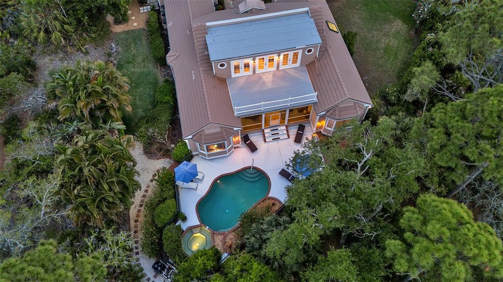 An aerial view shows a house with a pool, spa, and surrounding trees — 156 BISHOPS COURT ROAD, OSPREY, FL