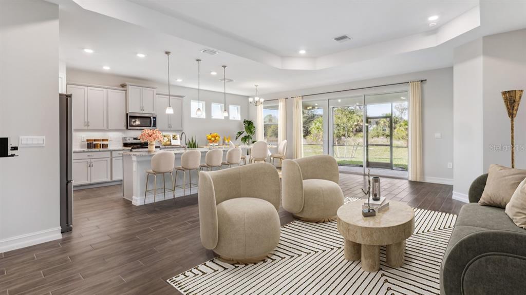 An open-concept living room and kitchen feature light cabinetry, tile flooring, and sliding glass doors — 12736 SEAGRASS DRIVE, PUNTA GORDA, FL